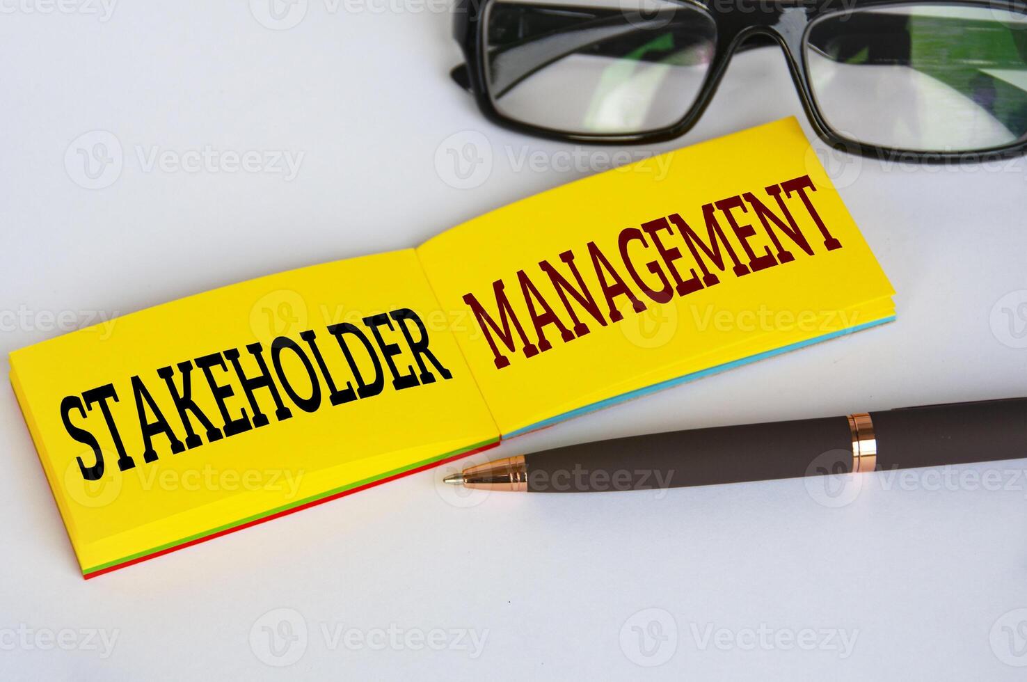 Stakeholder management text on yellow notepad with glasses and pen on white cover background. Business relationship concept photo