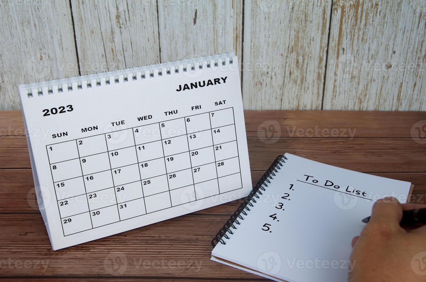 enero de 2023 calendario de escritorio blanco con cuaderno con texto - lista de tareas pendientes. concepto de calendario y lista de tareas pendientes foto