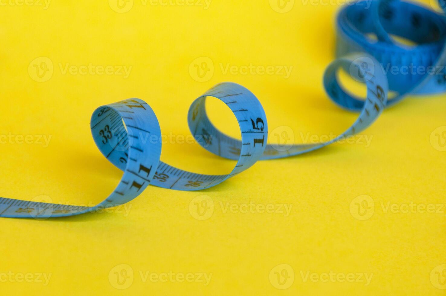 Blue measuring tapes on yellow cover background with customizable space for text or ideas. Copy space and weight loss concept photo