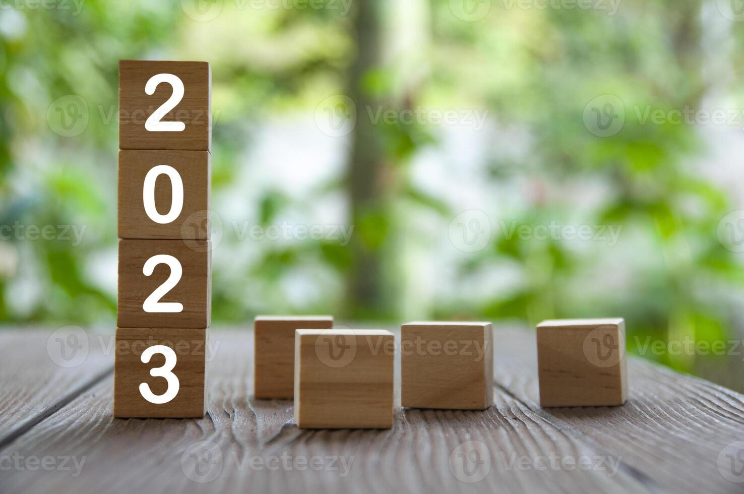 año 2023 sobre bloques de madera con fondo de naturaleza borrosa. concepto de año nuevo 2023 foto