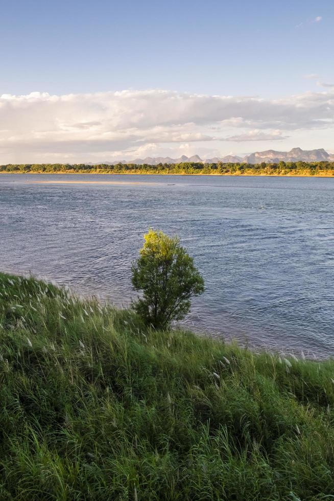 Green meadows along the Mekong River with small sandy beaches and stunning mountain views of Laos on a clear day. photo