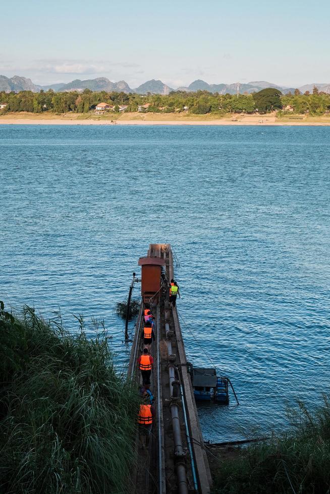 A group of people wearing life jackets are doing some activities along the Mekong River with beautiful Laos mountain views. photo