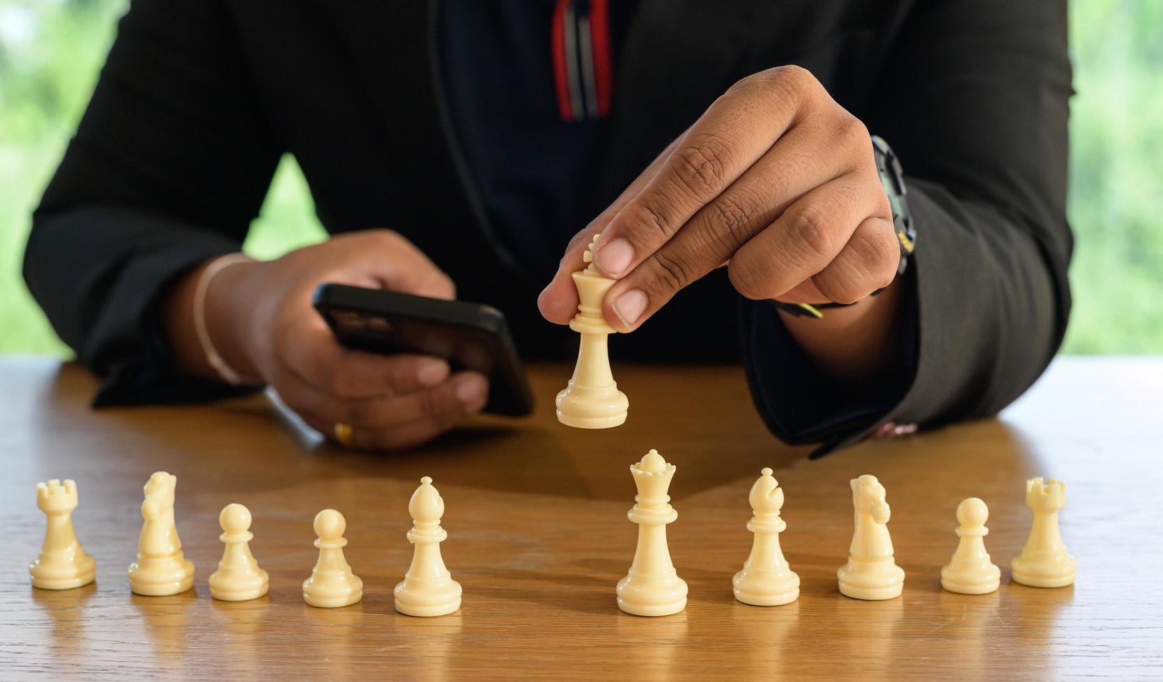 Businessman hands in black suite sitting and pointing chess king on vintage table meaning of planning and strategy. Decision and achievement goal concept. photo