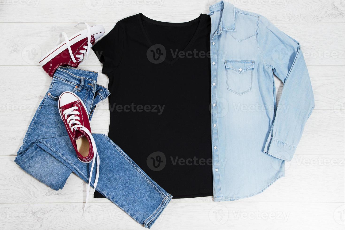 camiseta negra y zapatillas deportivas. maqueta de camiseta plana con accesorios de verano. jeans y zapatillas sobre fondo de piso de madera. copie el espacio plantilla lienzo en blanco. vista frontal superior. foto