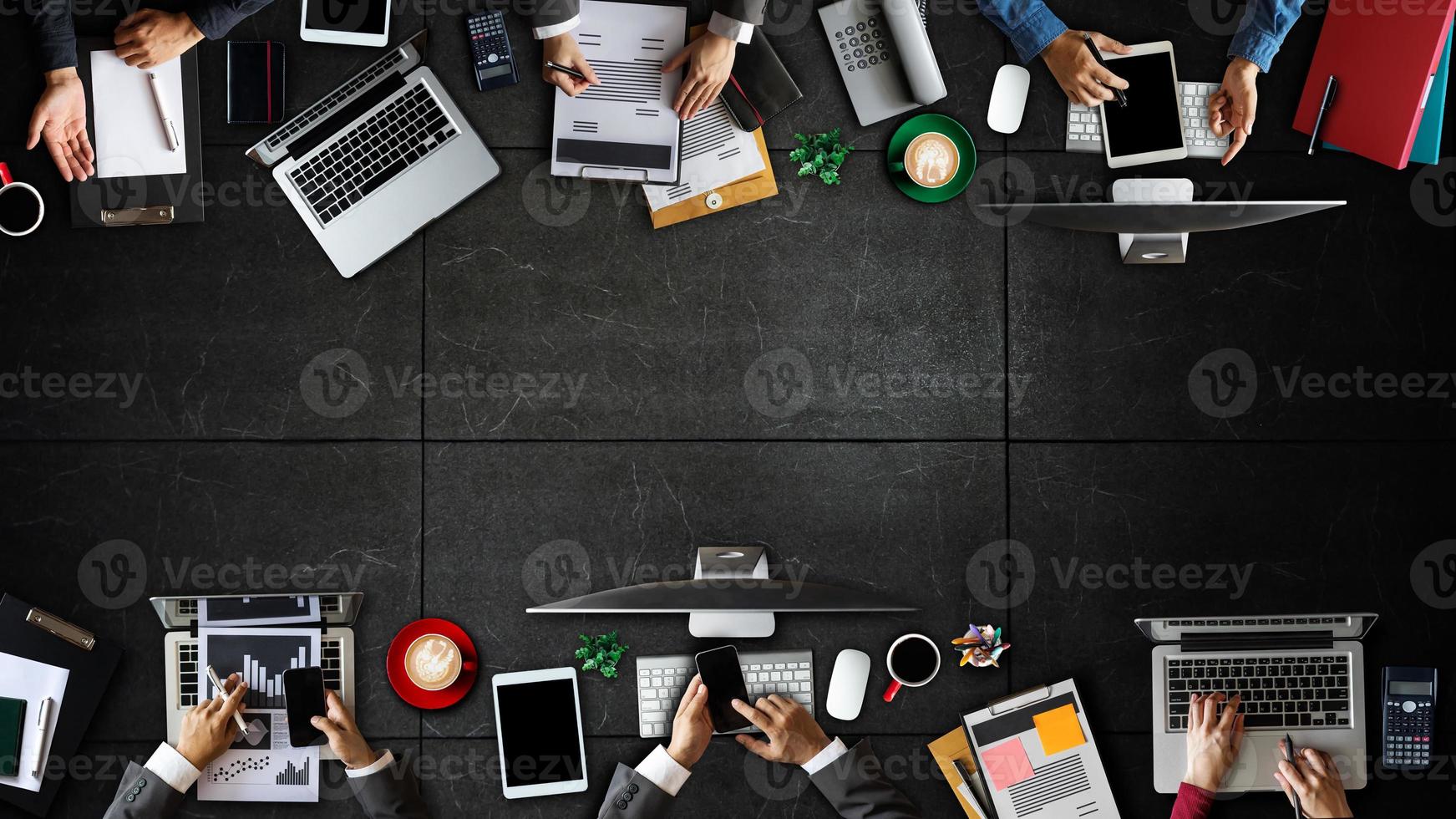 Top view of business Group of Multiethnic Busy People meeting with other in modern office with laptop computer, smartphone, tablet, coffee and document on table. photo