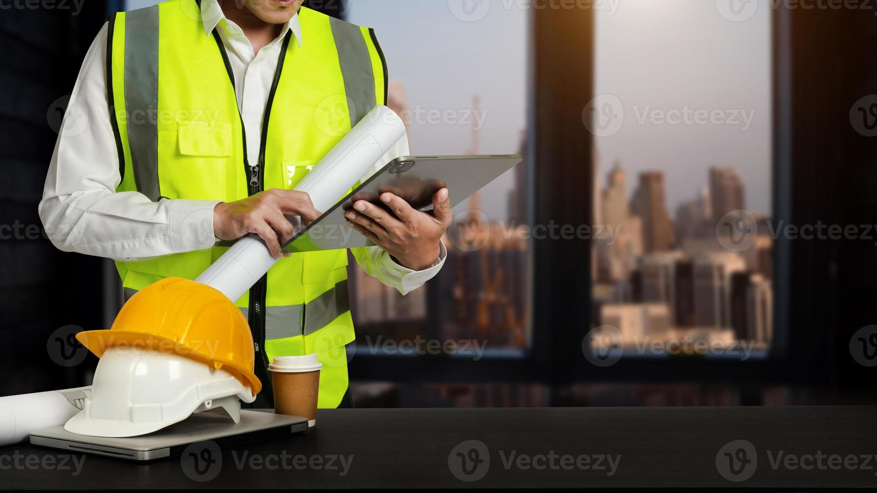 Engineer in helmet for workers security on modern office buildings and management on the construction drawing plan near laptop working in Engineering tools on desk photo