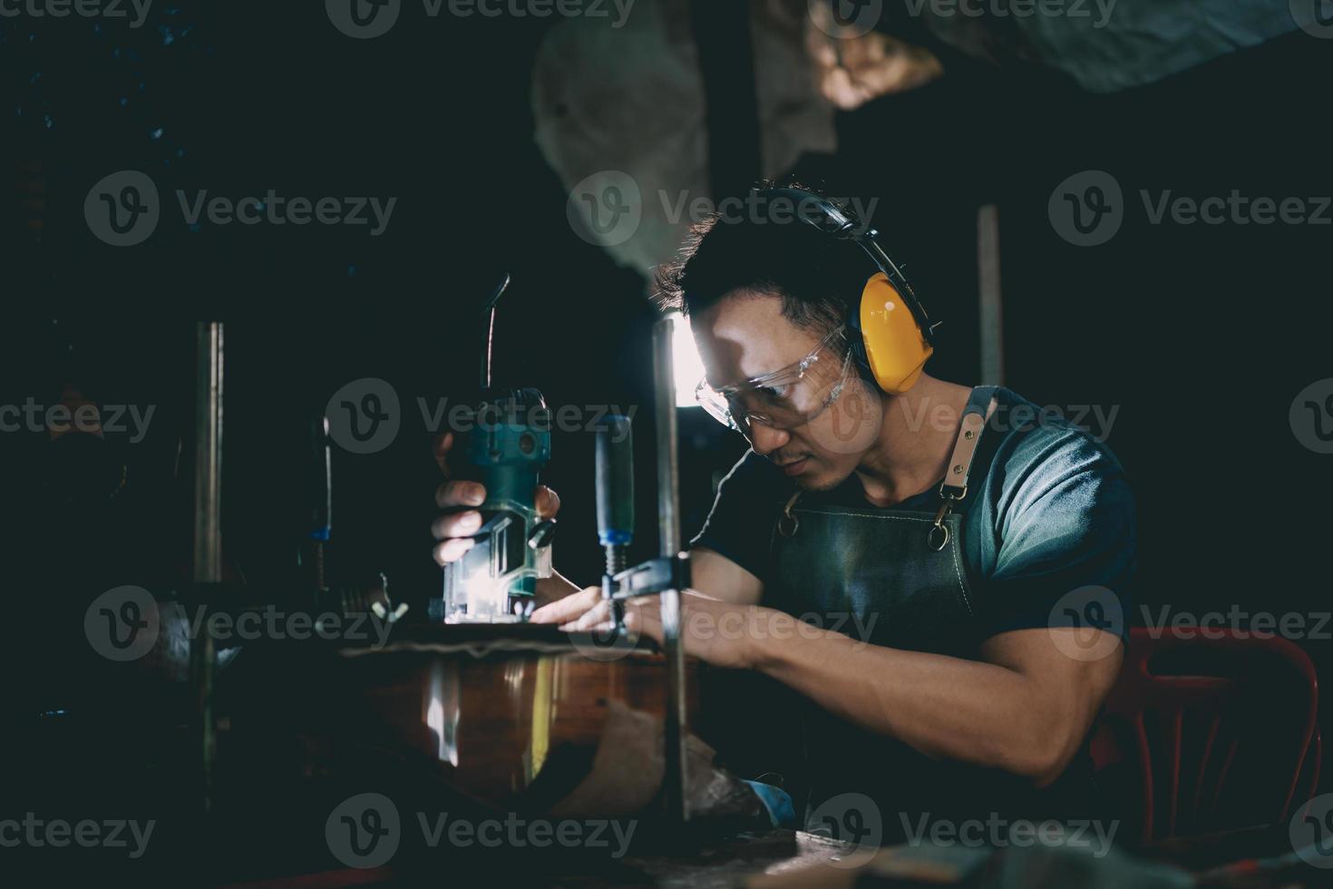 Guitar makers asian man making acoustic guitars in laboratory. Asian guitar maker builds high quality guitars for musicians handmade guitar shop. Working fine woodusic, tradition, ancient crafts. photo