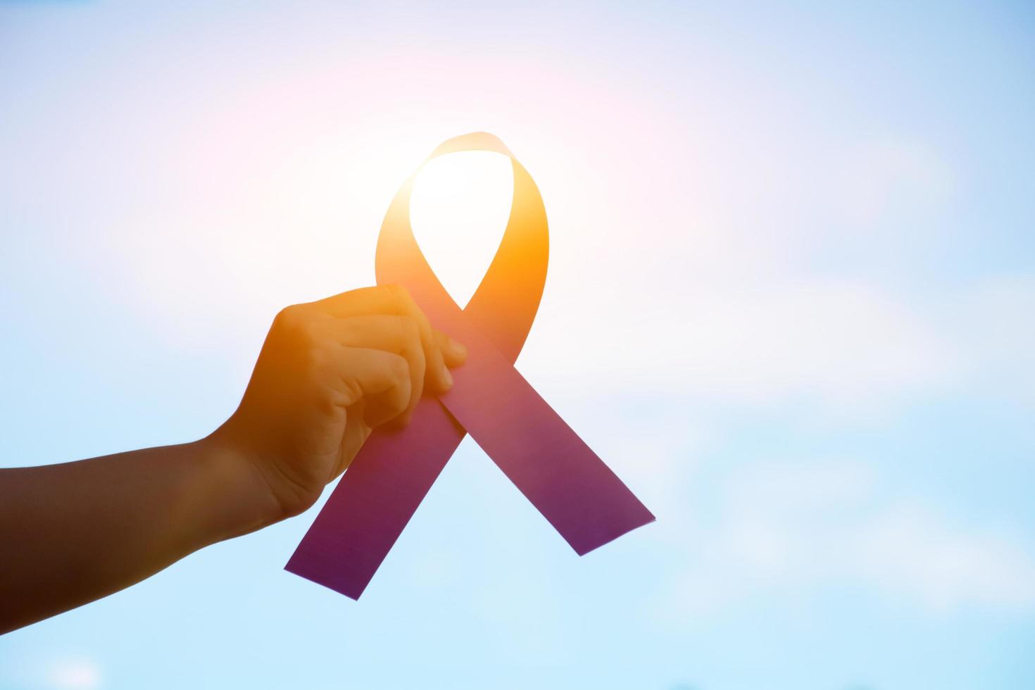 Pink paper ribbon holding in hands of female teenager to show and to call out all people around the world to support and to attend the breast cancer campaign of woman, soft and selective focus. photo