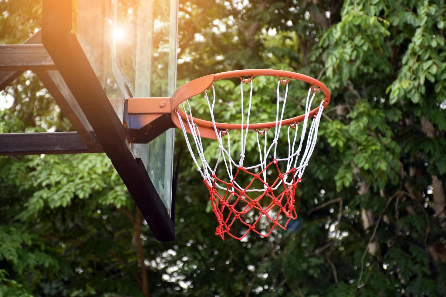 aro de baloncesto en el objetivo de tiro al aire libre, fondo borroso y editado por la luz del sol. enfoque suave y selectivo en el aro de baloncesto. foto