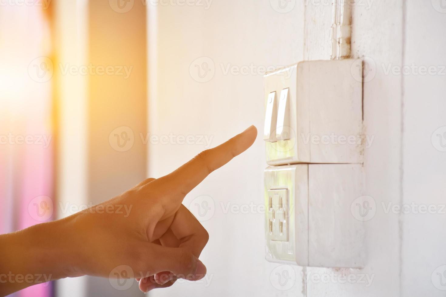Student is using his hand to turn off the light switch in front of his class before going back home, soft and selective focus, sunlight edited background. photo