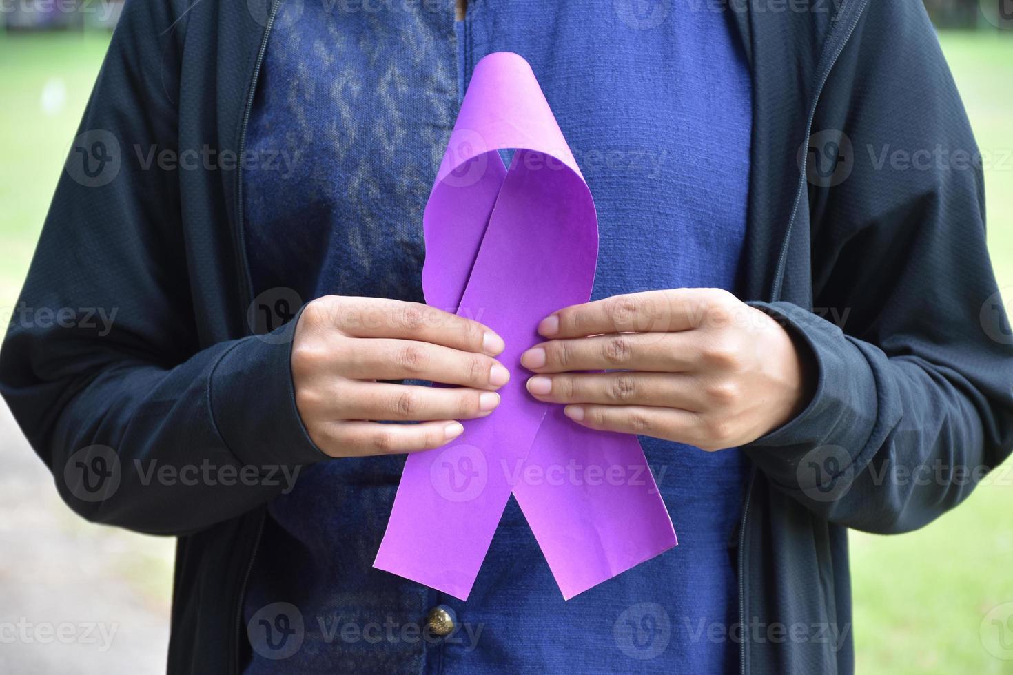 Pink paper ribbon holding in hands of female teenager to show and to call out all people around the world to support and to attend the breast cancer campaign of woman, soft and selective focus. photo