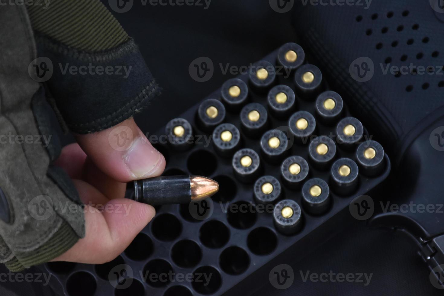 9mm bullet shells holding in fingers and placed near 9mm pistol on black leather background, soft and selective focus on bullet and fingers. photo