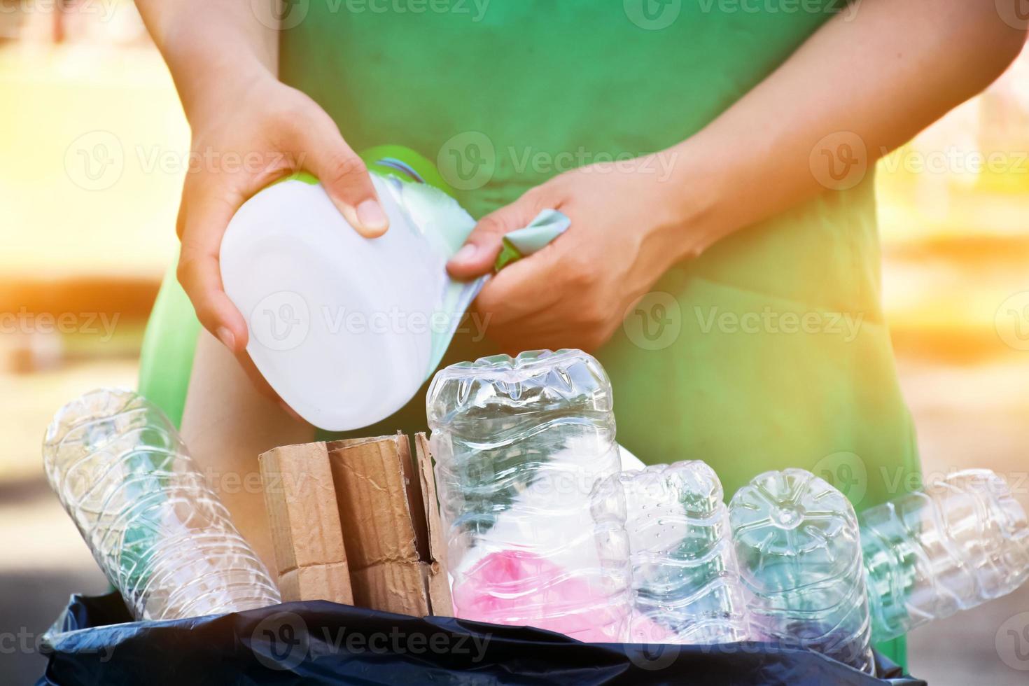 Houseowner is separiting bottles, paper, egg cartons and other stuffs in the black plastic bag in front of the house, concept for reducing global warming, saving our world, soft and selective focus. photo