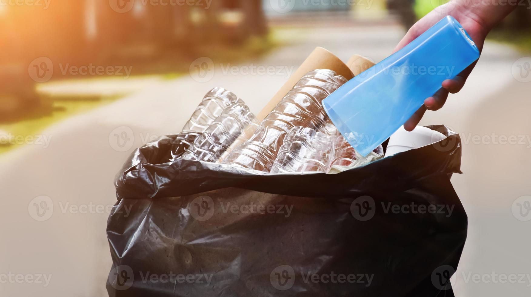 Houseowner is separiting bottles, paper, egg cartons and other stuffs in the black plastic bag in front of the house, concept for reducing global warming, saving our world, soft and selective focus. photo