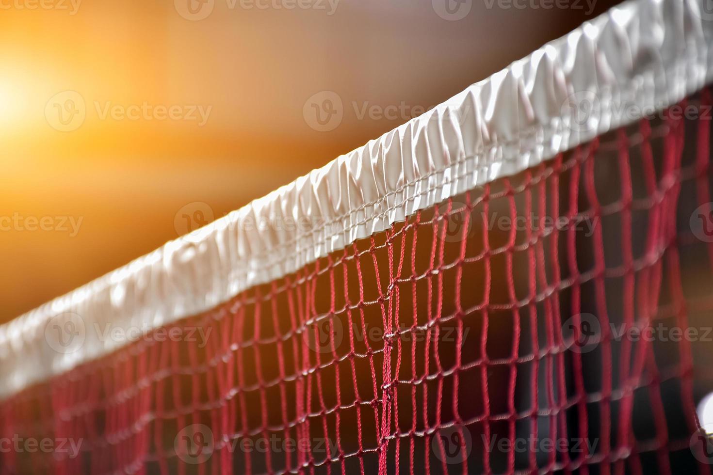 Cream white badminton shuttlecock and racket with neon light shading on green floor in indoor badminton court, blurred badminton background, copy space. photo