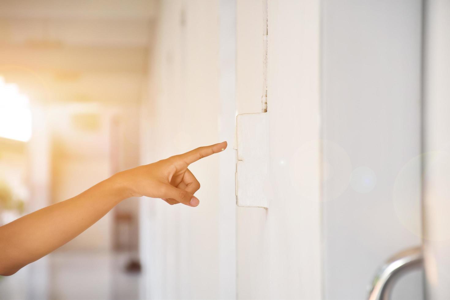 Student is using his hand to turn off the light switch in front of his class before going back home, soft and selective focus, sunlight edited background. photo