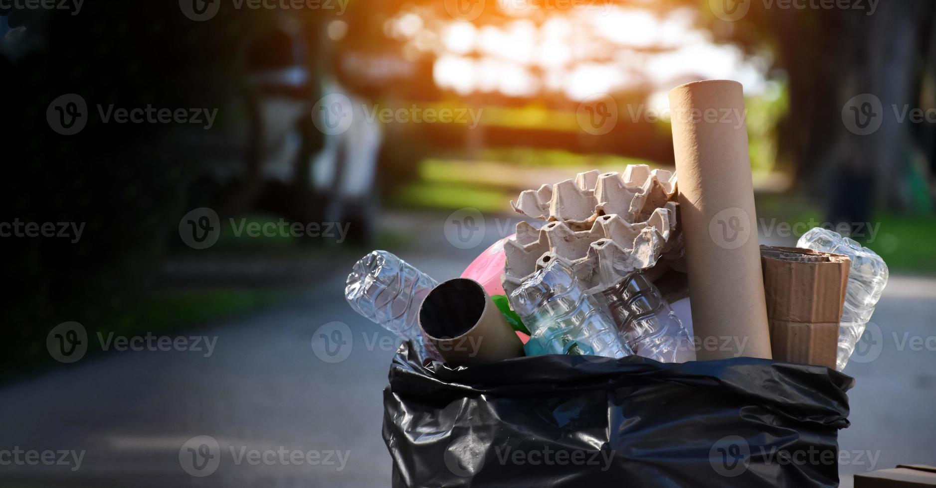 Houseowner is separiting bottles, paper, egg cartons and other stuffs in the black plastic bag in front of the house, concept for reducing global warming, saving our world, soft and selective focus. photo