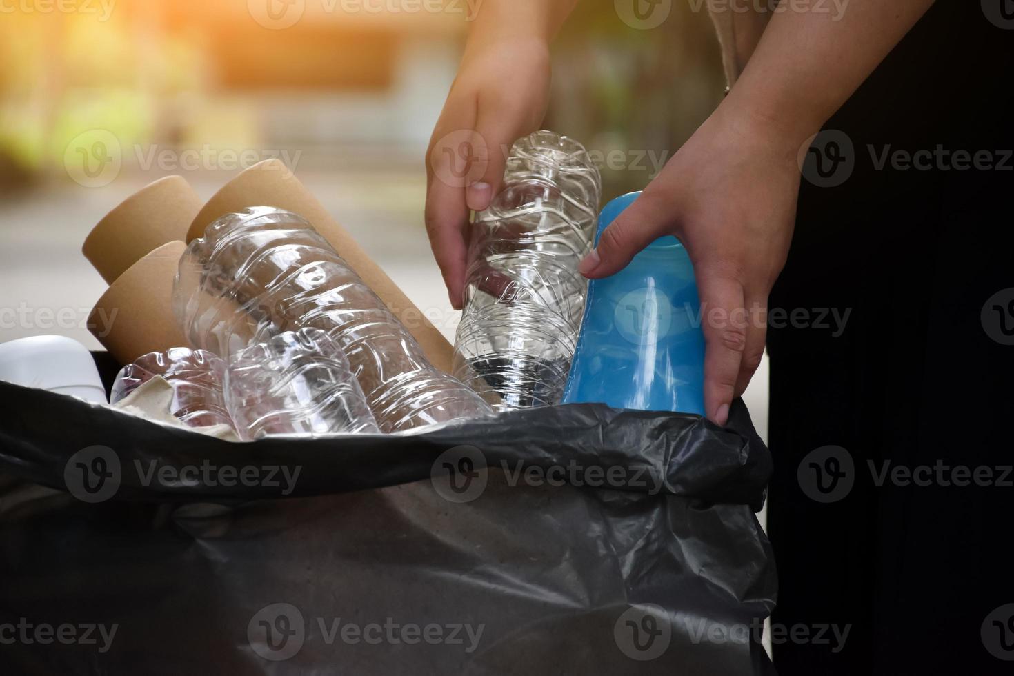 Houseowner is separiting bottles, paper, egg cartons and other stuffs in the black plastic bag in front of the house, concept for reducing global warming, saving our world, soft and selective focus. photo