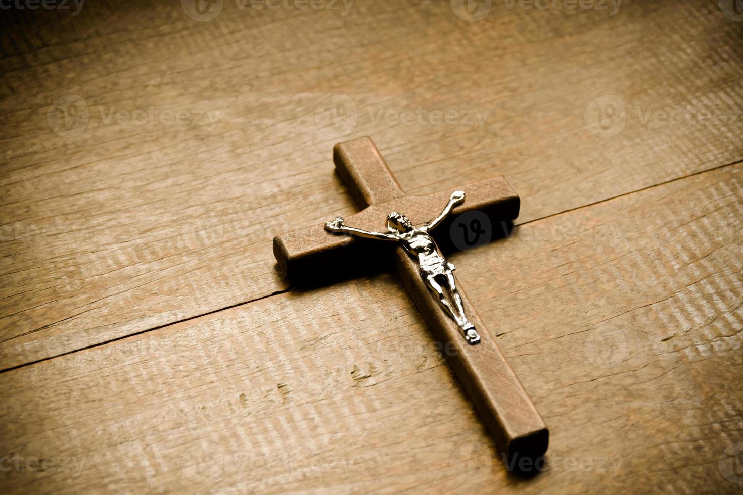 Closeup wooden cross which has a metal statue of crucified Jesus is on wooden table in a local church, soft and selective focus. photo