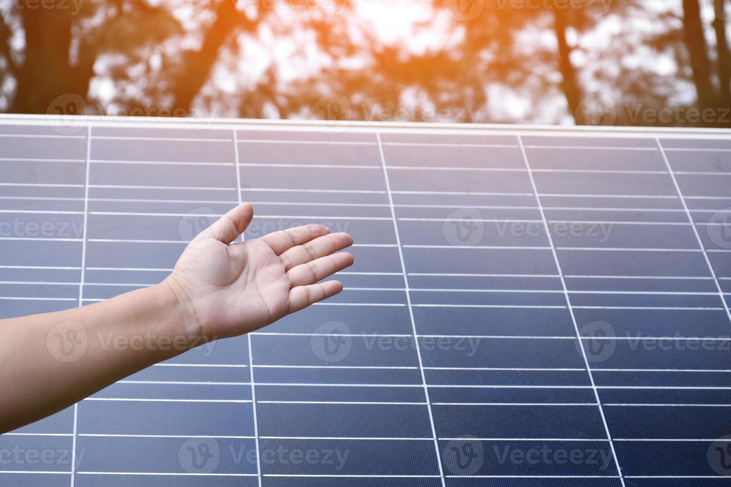 Photovoltaic or solar cell panel behind the left hand showing, soft and selective focus on hand, concept for presenting and showing the photovoltaic panel to store and use the natural power with human photo