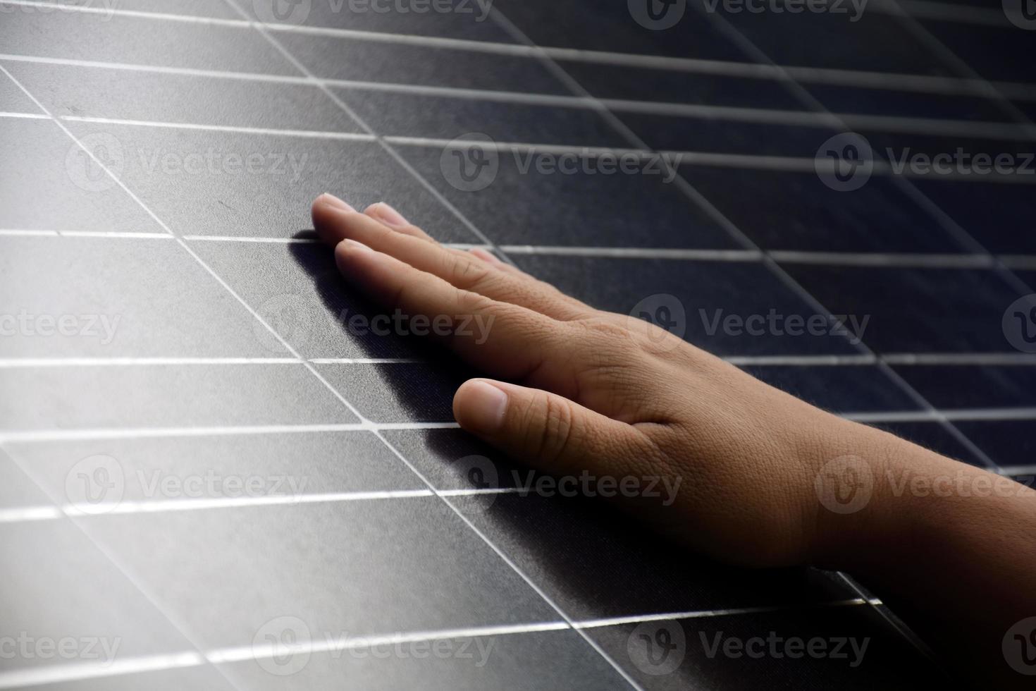 primer plano de la mano en el panel fotovoltaico o de células solares, enfoque suave y selectivo a mano, autocontrol del panel fotovoltaico al tocar la superficie, energía sostenible en el concepto de vida humana. foto