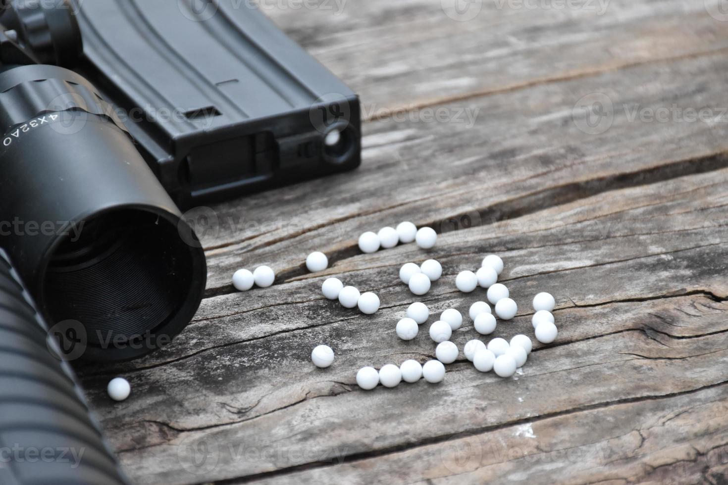 Closeup of white plastic bullets of airsoft gun or bb gun on wooden floor, soft and selective focus on white bullets. photo