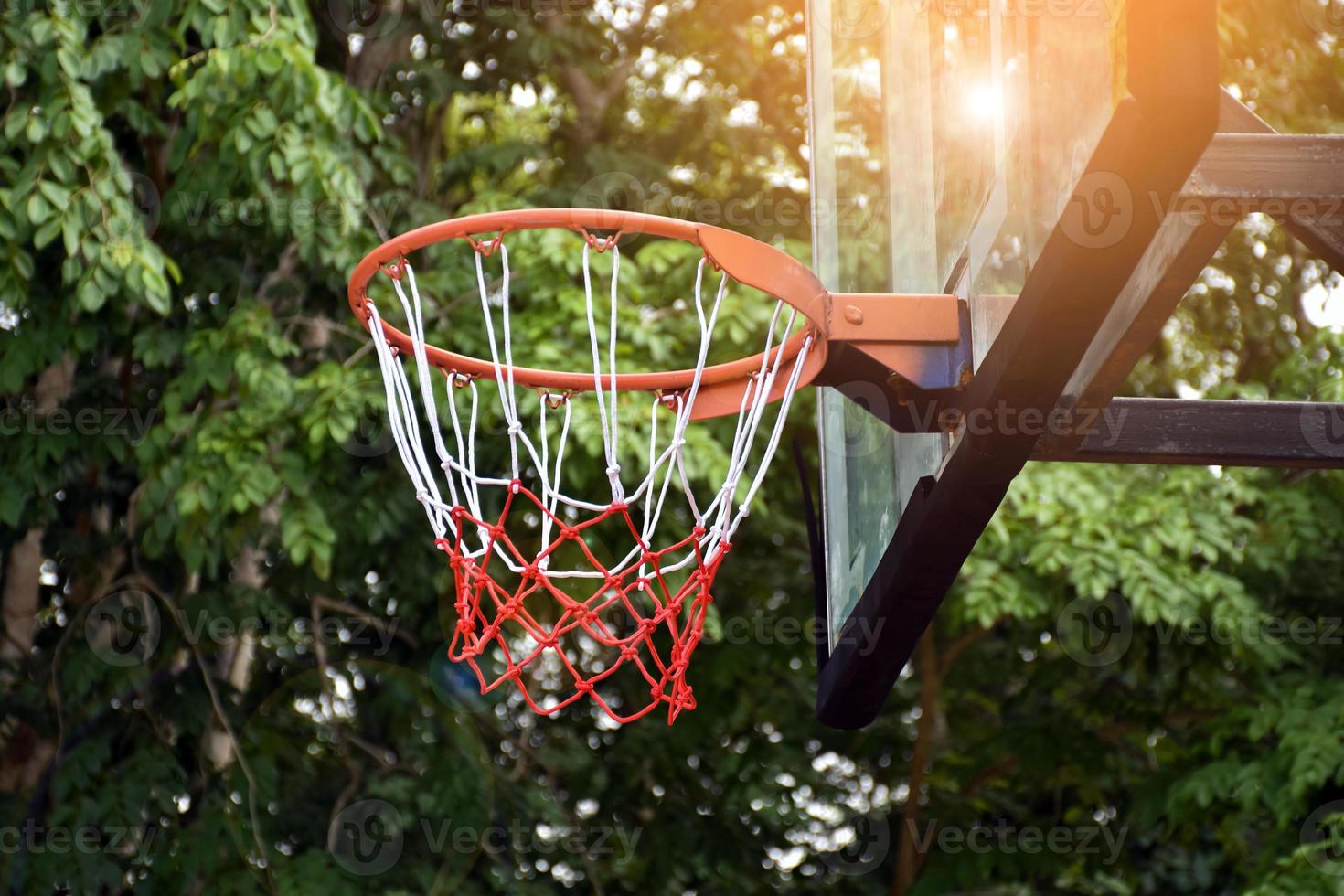 aro de baloncesto en el objetivo de tiro al aire libre, fondo borroso y editado por la luz del sol. enfoque suave y selectivo en el aro de baloncesto. foto