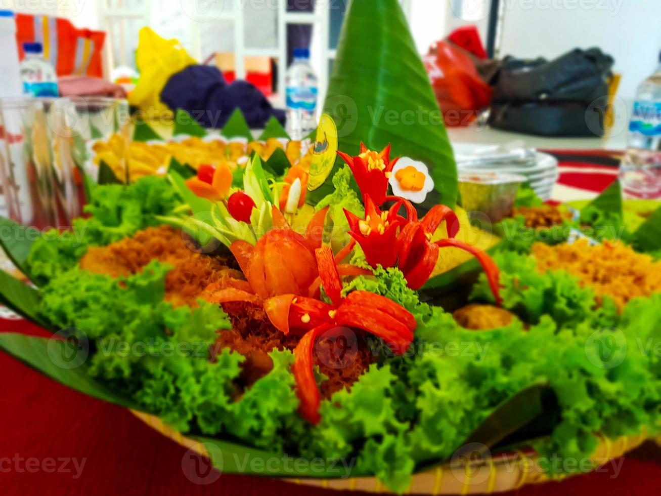 Nasi Tumpeng, yellow rice that is shaped into a cone and equipped with side dishes and vegetables around it. photo