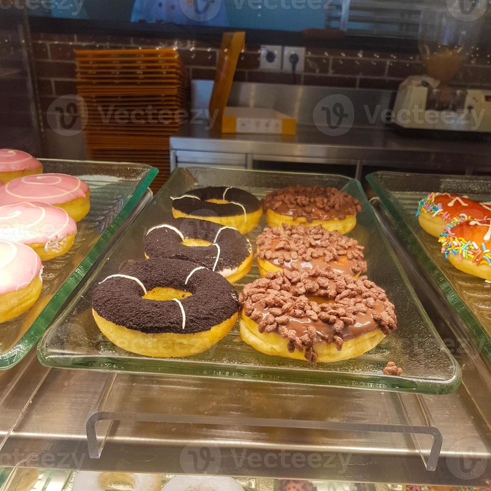 A hand is holding a donut with a unique taste. Shaped like a donut in general with a topping of an orange candy and orange candy flakes. photo