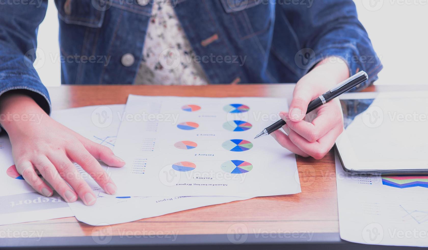 Front view of anonymous young woman analyst pointing with stylus at bar graph document with tablet placed sideways. photo
