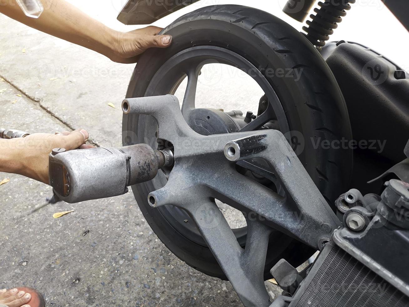 Close up of a motorcycle mechanic using an air gun to loosen the wheel nuts in a mechanical workshop photo