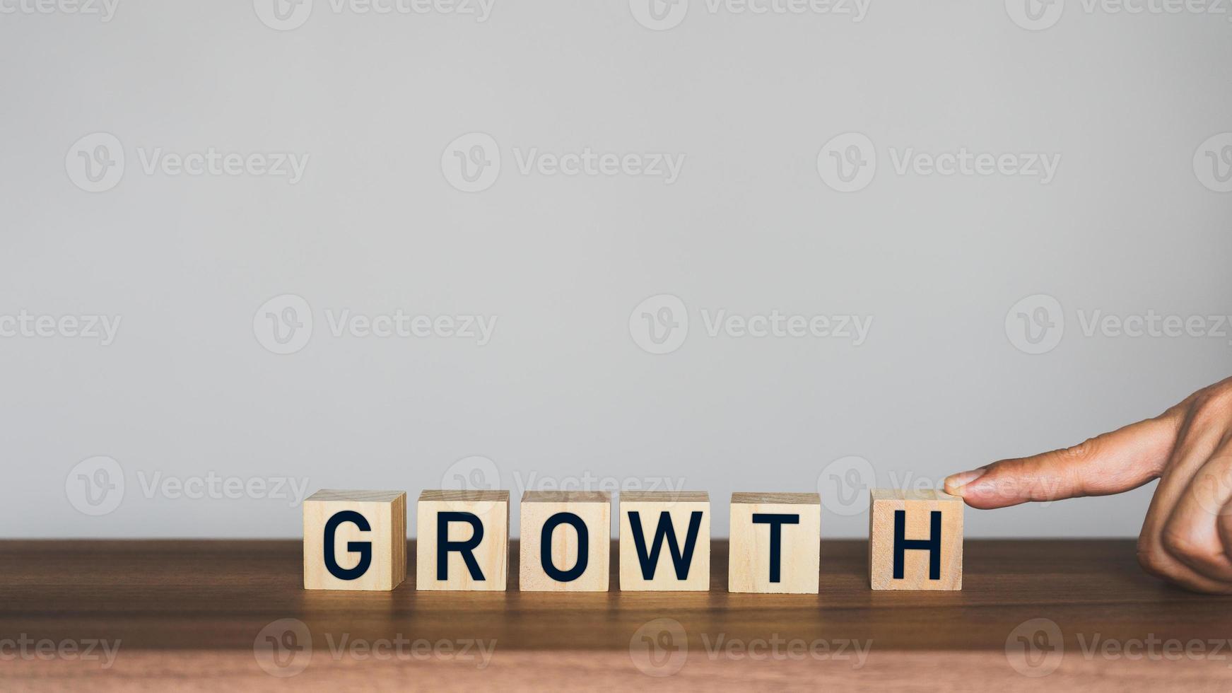 Man's hand scrolling the letter H to combine with the rest of the words to get the word growth on wooden cubes block. photo