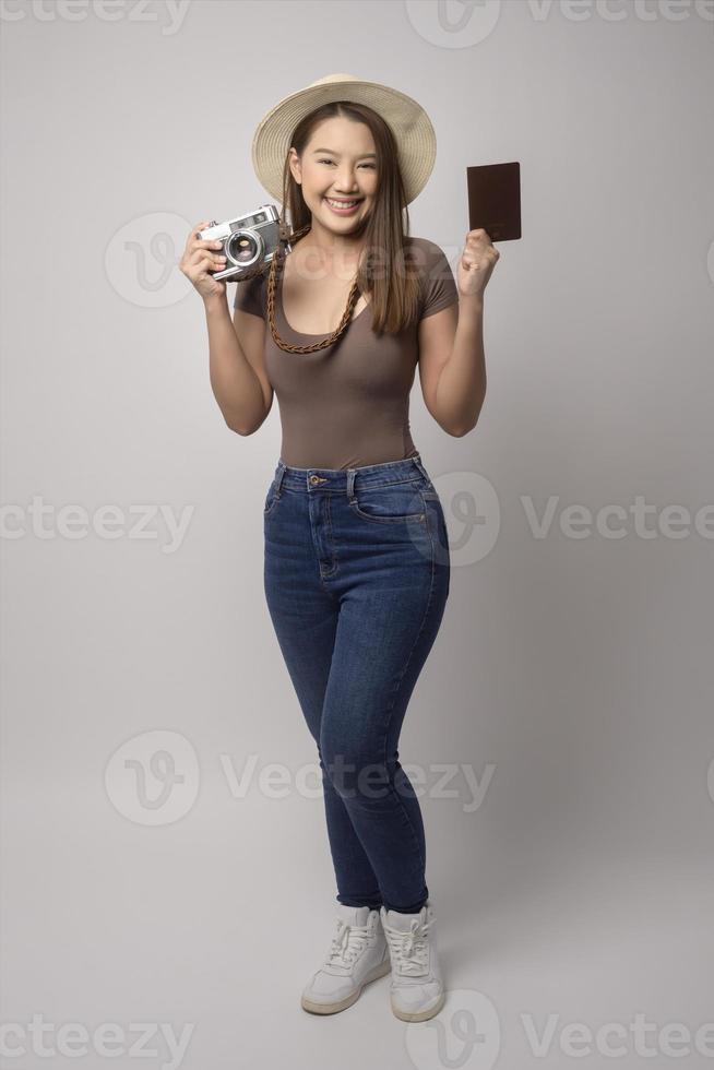 Young happy asian tourist woman over white background studio, travel and holidays concept. photo