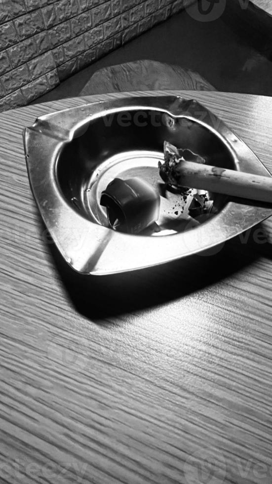 lit cigarette in a silver aluminum ashtray on the coffee shop table photo