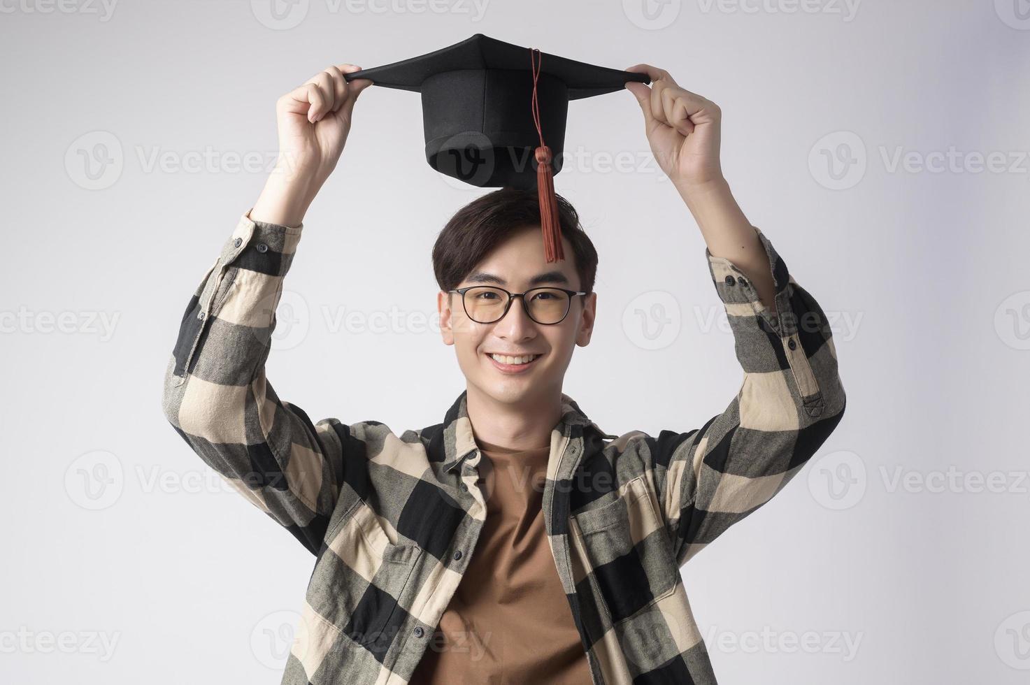 Young smiling man holding graduation hat, education and university concept photo