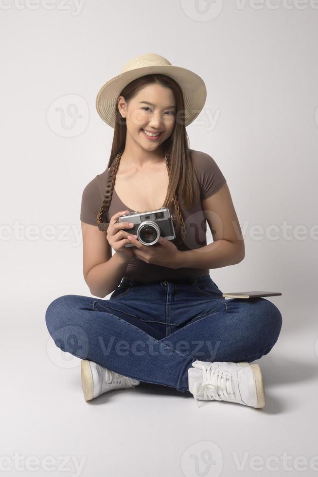 Young happy asian tourist woman over white background studio, travel and holidays concept. photo