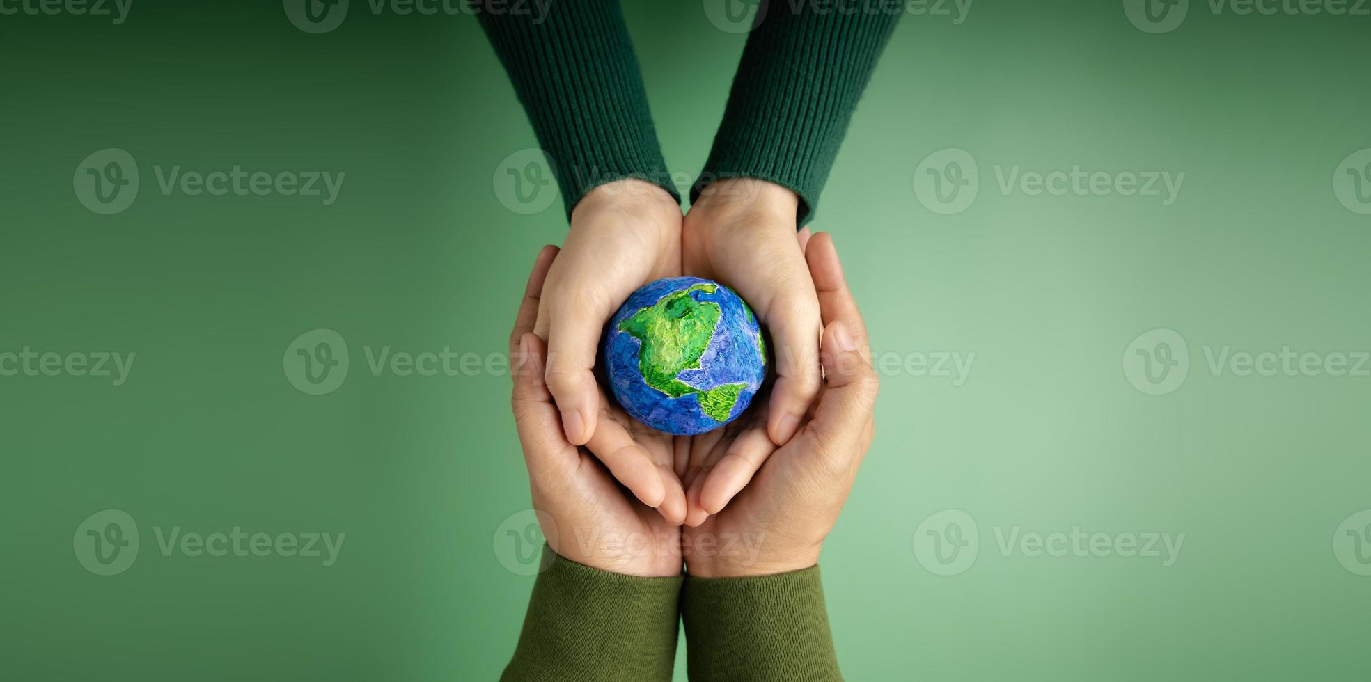 World Earth Day Concept. Green Energy, ESG, Renewable and Sustainable Resources. Environmental Care. Hands of People  Embracing a Handmade Globe. Protecting Planet Together. Top View photo