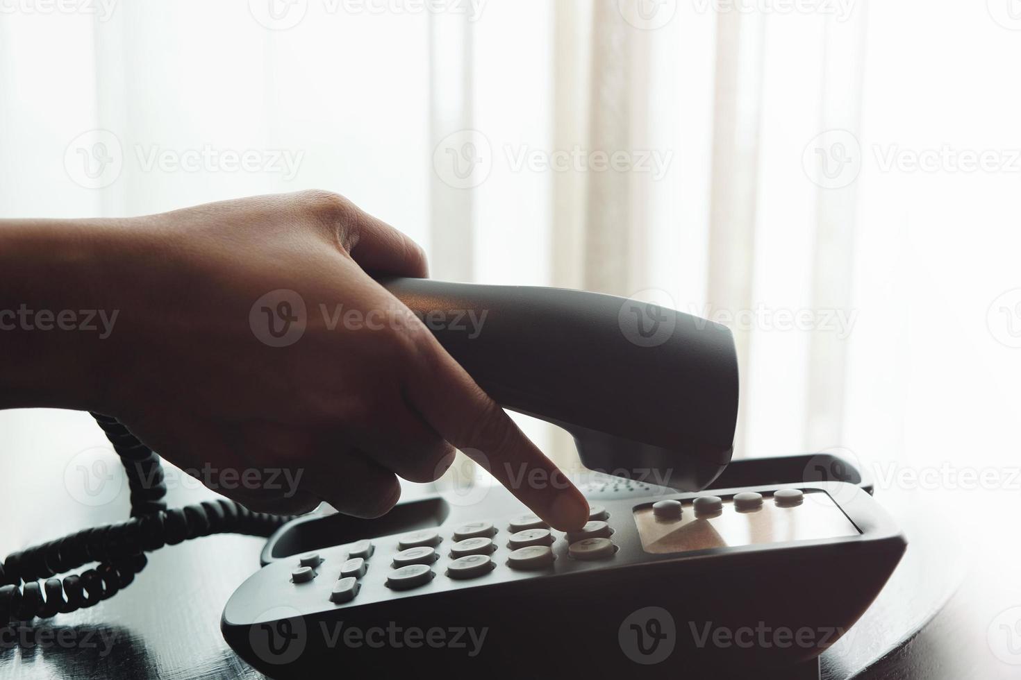 Close-up of Woman's Hand using a Telephone in House or Hotel near the Window photo