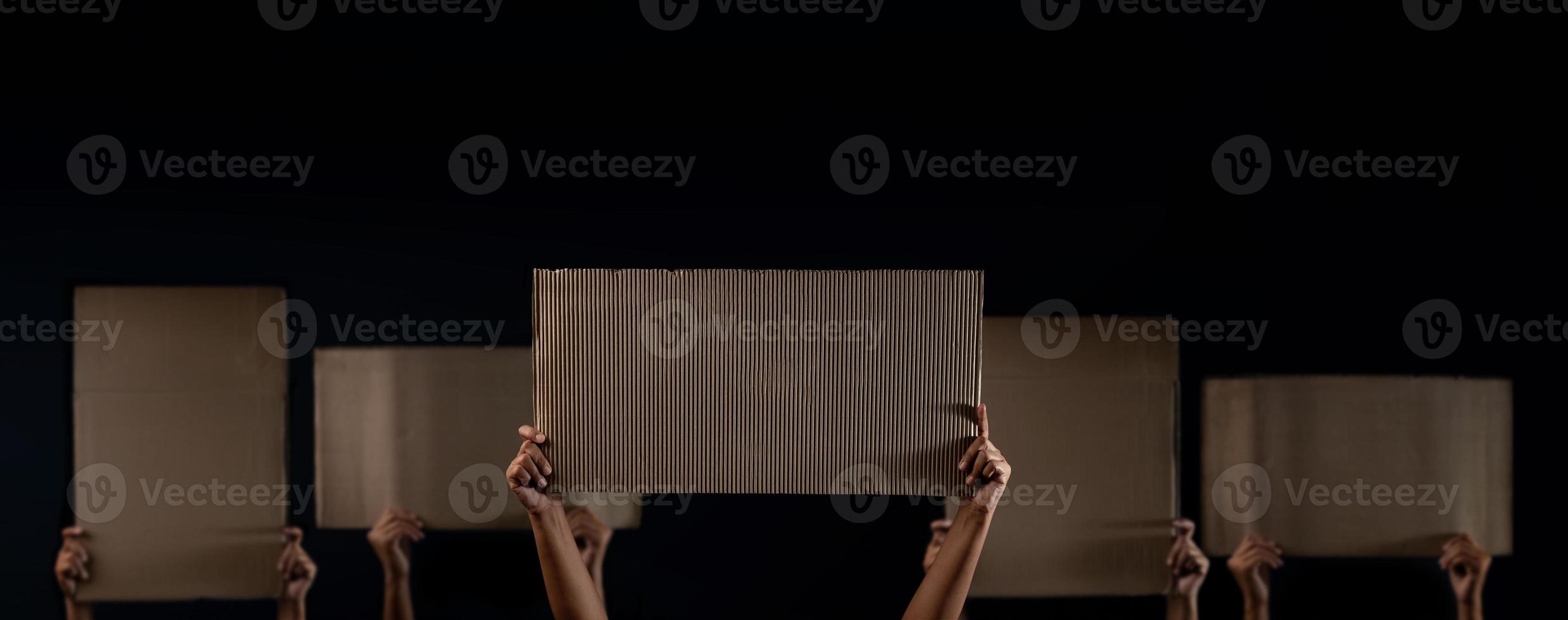 Protest , Mob or Expression Concept. Group of People Raised a Blank Corrugated Paper. Speech Template Texture Background. Front View and Dark tone photo