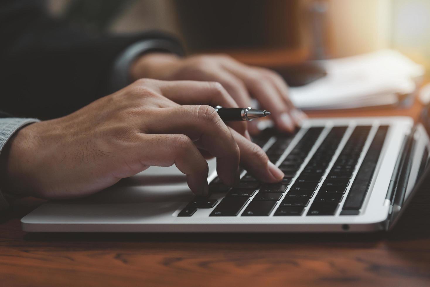 trabajo de la mano del hombre de negocios en la computadora portátil con teclado en la mesa de la oficina de cerca.concepto de negocio y tecnología. foto