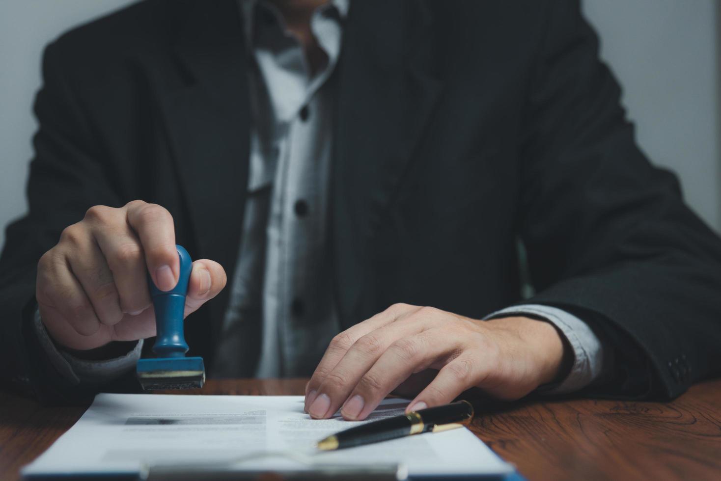 Man stamping approval of work finance banking or investment marketing documents on desk. photo