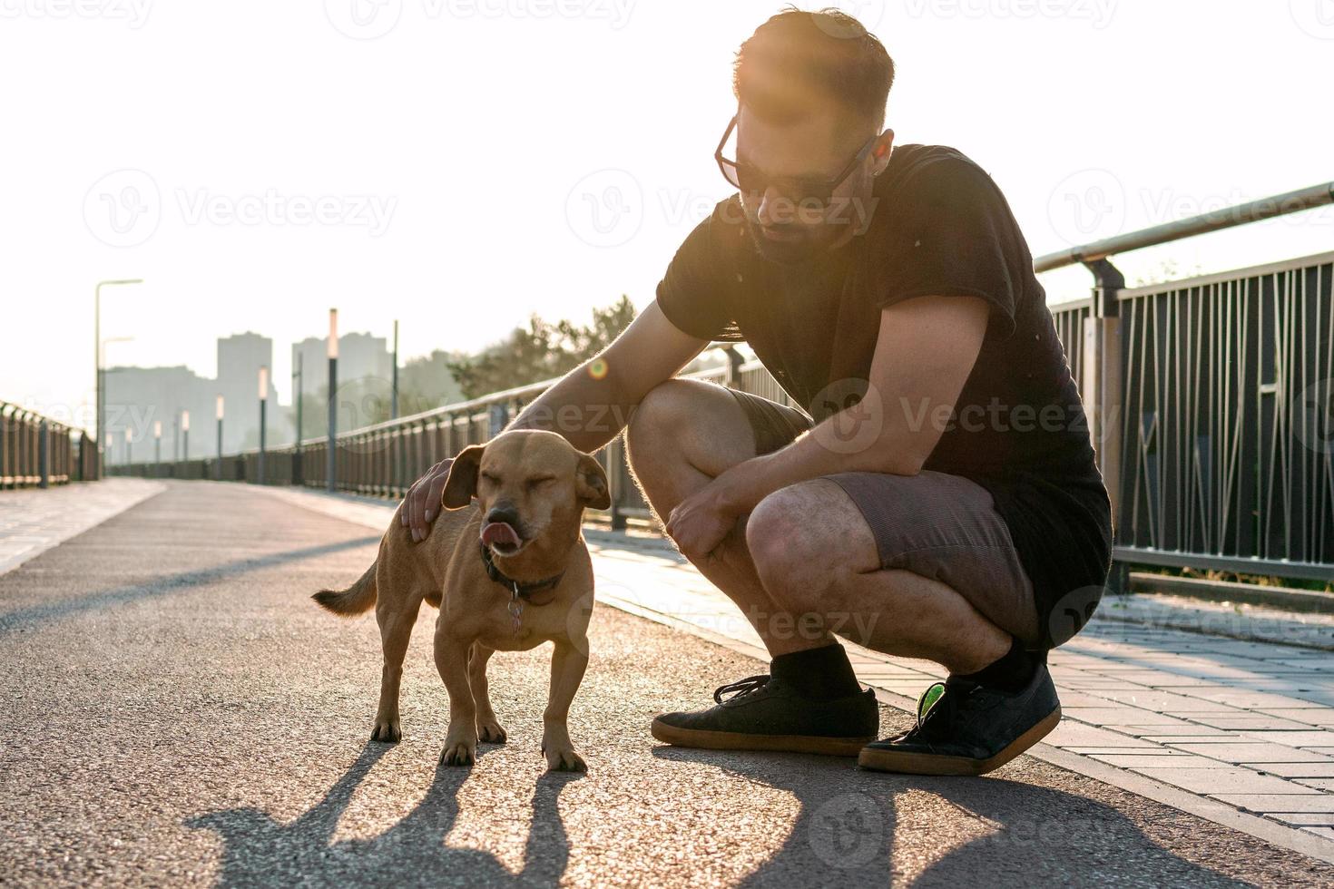 un joven apuesto camina con su perro por la mañana en una calle vacía de la ciudad. foto