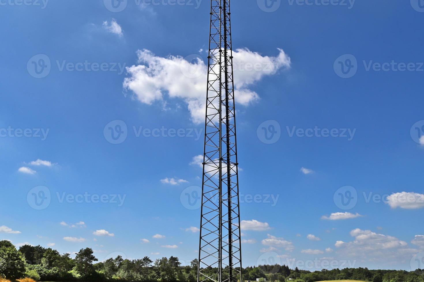 Electric antenna and communication transmitter tower in a northern european landscape against a blue sky photo