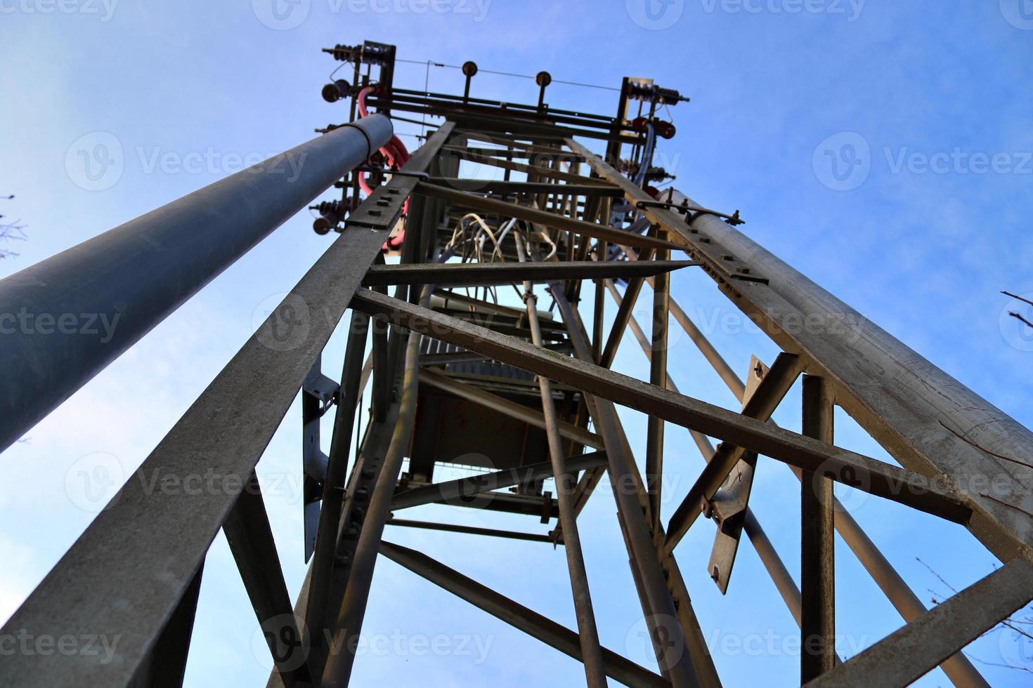 Electric antenna and communication transmitter tower in a northern european landscape against a blue sky photo