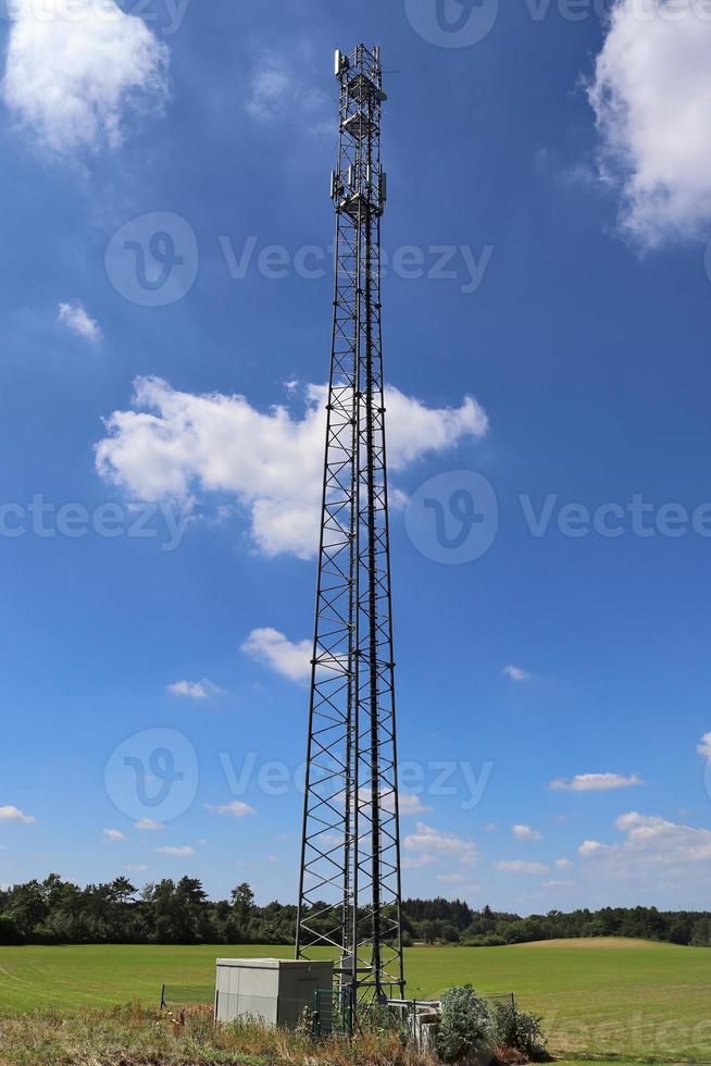 Electric antenna and communication transmitter tower in a northern european landscape against a blue sky photo