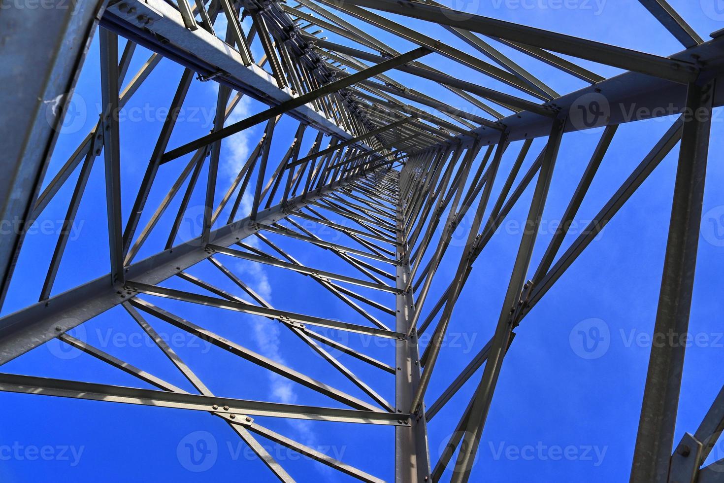 Electric antenna and communication transmitter tower in a northern european landscape against a blue sky photo