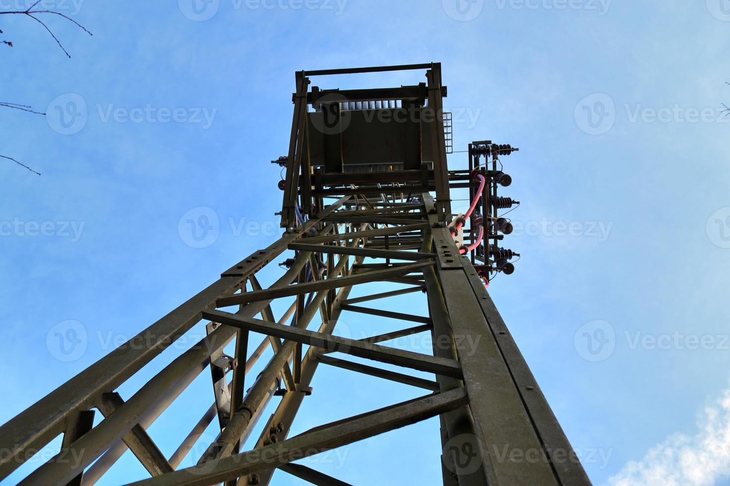 Electric antenna and communication transmitter tower in a northern european landscape against a blue sky photo