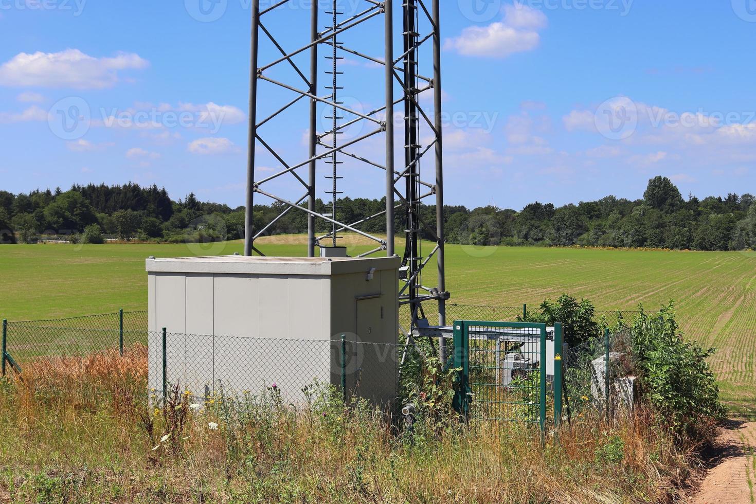 Electric antenna and communication transmitter tower in a northern european landscape against a blue sky photo