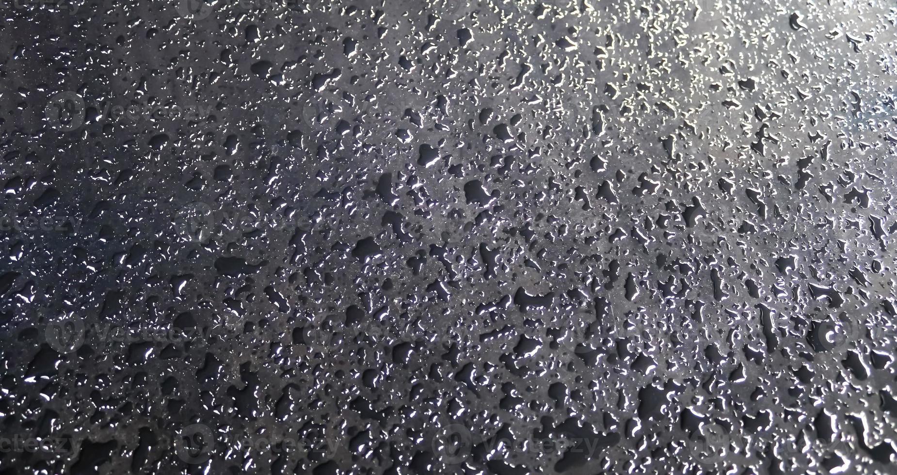 Rain drops on a black metallic car surface in a closeup view. photo