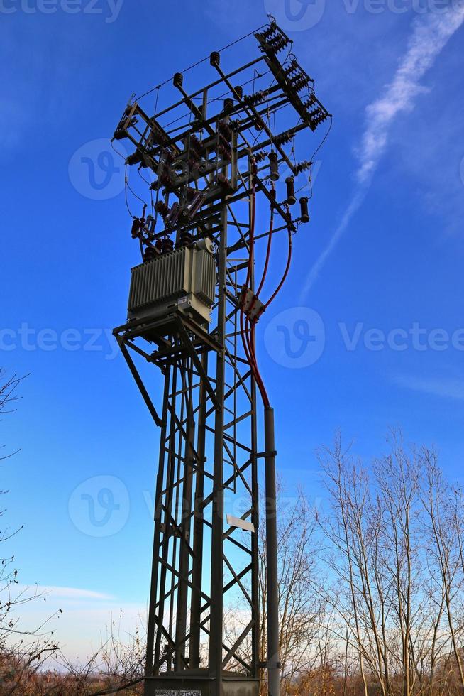 Electric antenna and communication transmitter tower in a northern european landscape against a blue sky photo